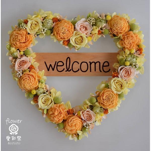 縦24cm　横26cm（リース代金11,000円　プレート代金500円）オレンジ色のソーラーフラワー淡いイエローとピンクのバラやオレンジ色のお花でカラフルなハートリース。プリザーブドフラワーのウェルカムリースです。プレートの文字は手書きです...