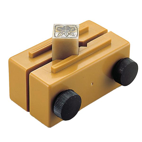 サイズ：100×52×50mm 固定：8〜35mm角の印材まで鈕や側面の彫刻に便利な横溝付きのプラスチック製印台です。印材とバイス面がフラットになるので共けずり(平面だし)が可能です。