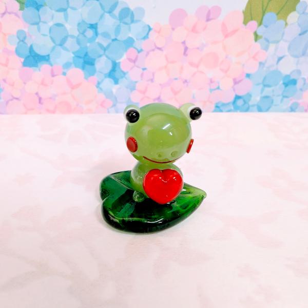 カエル葉のりハート持ちのガラス細工の置物です。【大きさ】約高さ２５ミリ　　横幅２５ミリ　　　　　奥行２０ミリ＊商品は一つ一つ手造りのため大きさや色合いが写真と異なる場合がありますのでご了承をお願い致します。