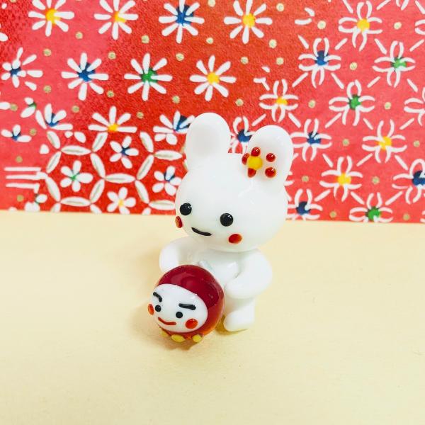ウサギとだるまのガラス細工の置物です。【大きさ】約高さ３０ミリ　　横幅１６ミリ　　　　　奥行２７ミリ＊商品は一つ一つ手造りのため大きさや色合いなどが写真と異なる場合がありますのでご了承をお願い致します。