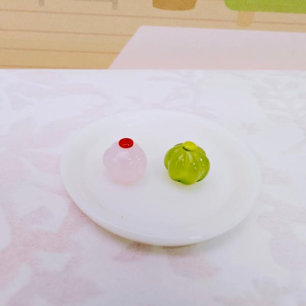 和菓子（ミニ）2個セットのガラス細工の置物です。お皿はディスプレイです。【大きさ】約高さ６ミリ　　横幅７ミリ　　　　　奥行７ミリ＊商品は一つ一つ手造りのため大きさや色合いなどが写真と異なる場合がありますのでご了承をお願い致します。