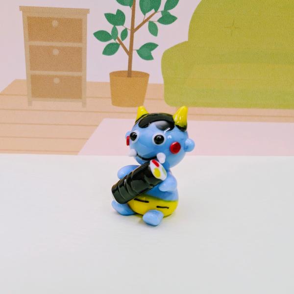 青鬼と恵方巻のガラス細工の置物です。【大きさ】約高さ２８ミリ　　横幅１８ミリ　　　　　奥行１８ミリ＊商品は一つ一つ手造りのため大きさや色合いなどが写真と異なる場合がありますのでご了承をお願い致します。