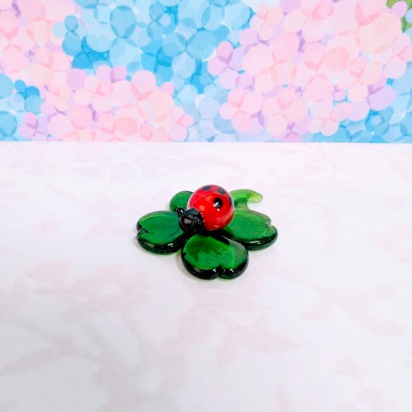 てんとう虫とよつばのガラス細工の置物です。【大きさ】約高さ１１ミリ　横幅２３ミリ　　　　　奥行３０ミリ＊商品は一つ一つ手造りのため大きさや色合いなどが写真と異なる場合がありますのでご了承をお願い致します。