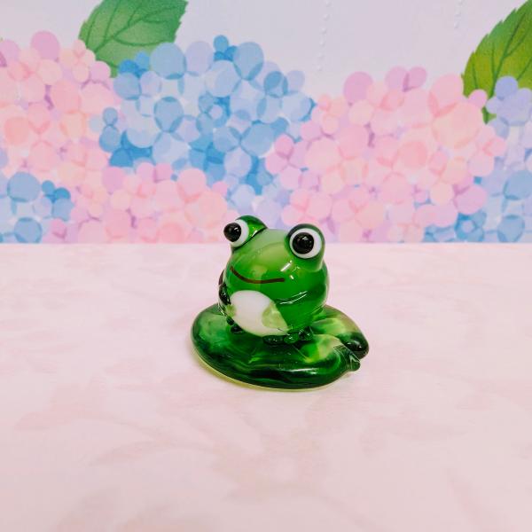 丸カエルと蓮の葉のガラス細工の置物です。【大きさ】約高さ２０ミリ　　横幅２５ミリ　　　　　奥行２５ミリ＊商品は一つ一つ手造りのため大きさや色合いなどが写真と異なる場合がありますのでご了承をお願い致します。