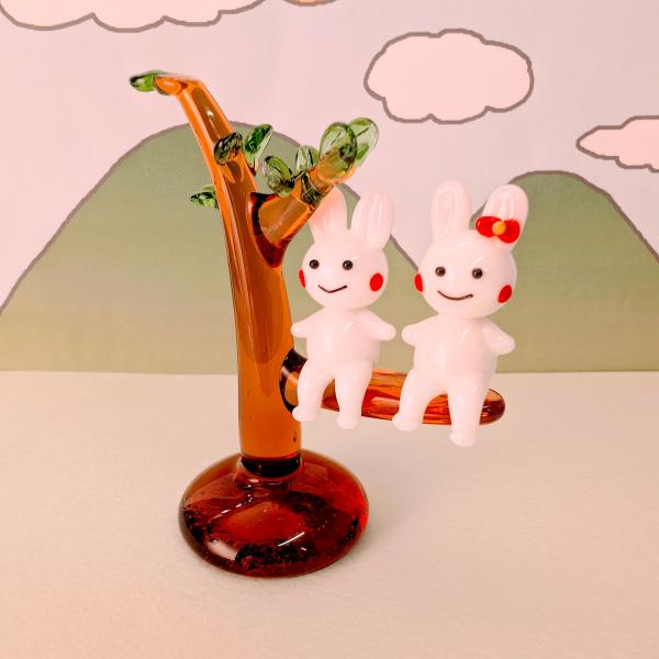 ウサギペアと木のガラス細工の置物です。【大きさ】約高さ７０ミリ　　横幅６０ミリ　　　　　奥行３２ミリ＊商品は一つ一つ手造りのため大きさや色合いなどが写真と異なる場合がありますのでご了承をお願い致します。