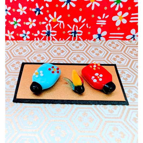 羽子板セット（ミニ）台紙付のガラス細工の置物です。【大きさ】約高さ１６ミリ　　横幅１０ミリ　　　　　厚さ4ミリ　　（羽子板の大きさ）＊商品は一つ一つ手造りのため大きさや色合いなどが写真と異なる場合がありますのでご了承をお願い致します。　　　　　