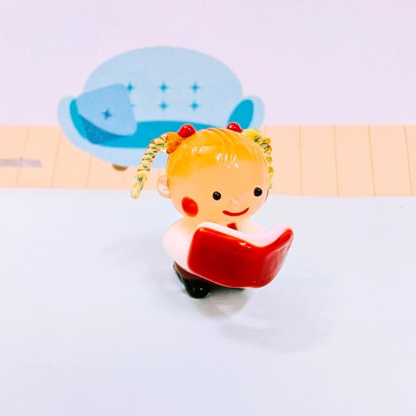 女の子と本（赤）のガラス細工の置物です。【大きさ】約高さ２５ミリ　　横幅２５ミリ　　　　　奥行２０ミリ＊商品は一つ一つ手造りのため大きさや色合いなどが写真と異なる場合がありますのでご了承をお願い致します。