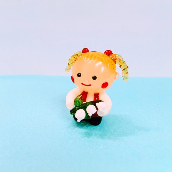 女の子とスズランのガラス細工の置物です。【大きさ】約高さ２５ミリ　　横幅２５ミリ　　　　　奥行２０ミリ＊商品は一つ一つ手造りのため大きさや色合いなどが写真と異なる場合がありますのでご了承をお願い致します。
