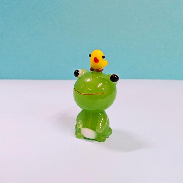 カエルお座りとヒヨコのガラス細工の置物です。【大きさ】約高さ30ミリ　　横幅１6ミリ　　　　　奥行１6ミリ＊商品は一つ一つ手造りのため大きさや色合いなどが写真と異なる場合がありますのでご了承をお願い致します。