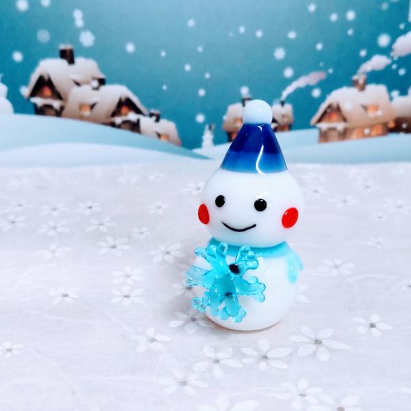 雪だるまと雪の結晶（青）のガラス細工の置物です。【大きさ】約高さ３５ミリ　　横幅１７ミリ　　　　　奥行２０ミリ＊商品は一つ一つ手造りのため大きさや色合いなどが写真と異なる場合がありますのでご了承をお願い致します。