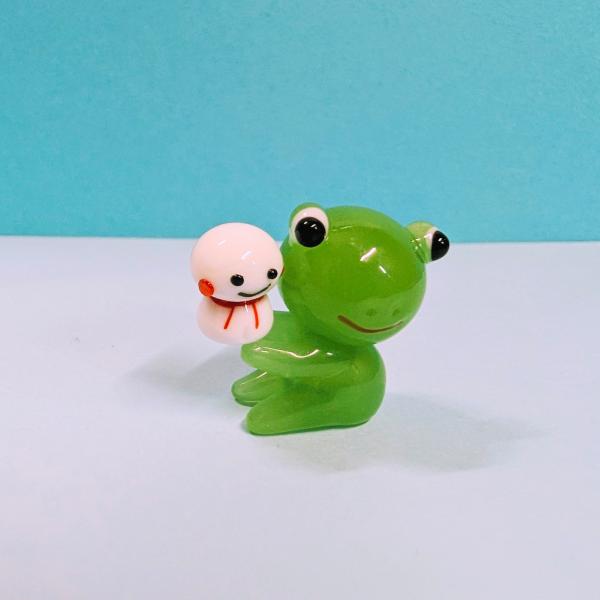 カエルとてるてる坊主のガラス細工の置物です。【大きさ】約高さ２３ミリ　　横幅１７ミリ　　　　　奥行１５ミリ＊商品は一つ一つ手造りのため大きさや色合いなどが写真と異なる場合がありますのでご了承をお願い致します。