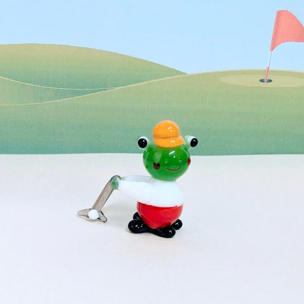 カエルのゴルフのガラス細工の置物です。【大きさ】約高さ２８ミリ　　横幅３０ミリ　　　　　奥行１１ミリ＊商品は一つ一つ手造りのため大きさや色合いなどが写真と異なる場合がありますのでご了承をお願い致します。