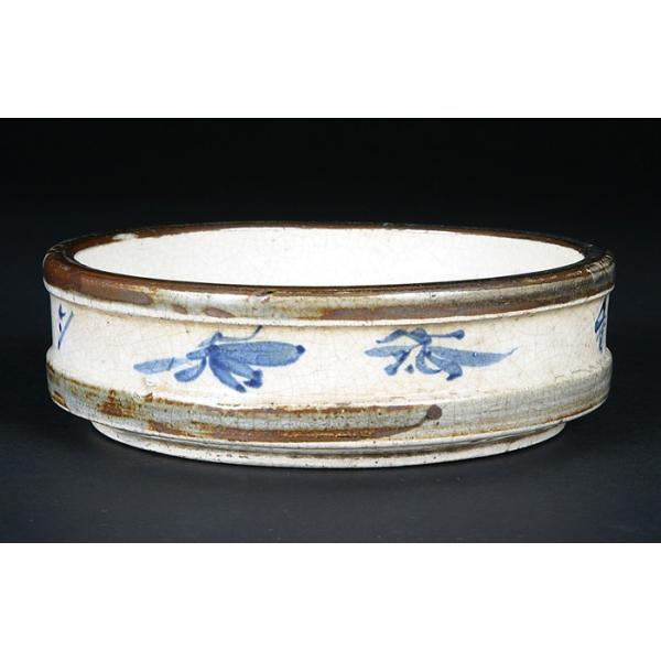 サイズ：口径15.5cm高4.7cm商品解説産地は特定できませんが、淡い発色の白釉に貫入が入った味のある仕上がりの丸水盤。染付であしらわれた絵付や文字がワンポイントとなった面白い逸品です。時代的にもかなり古いもので古色感は抜群。下側面のホツ...