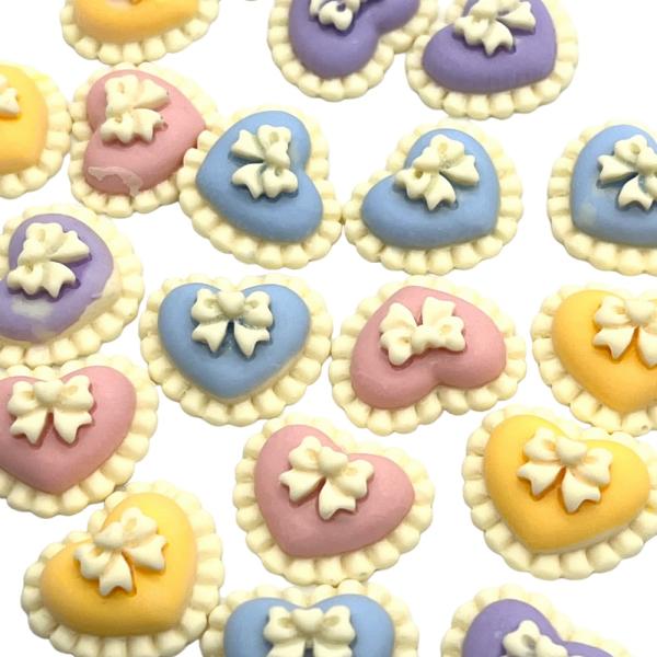 ご覧いただきましてありがとうございます。ハートのデコパーツで真ん中にリボンがついているキュート！アクリル製で軽くて使いやすくアレンジ幅のあるパーツです。使いやすいサイズなのでいろいろな用途でご使用ください。■サイズ：約2cm×2cm厚み約6...