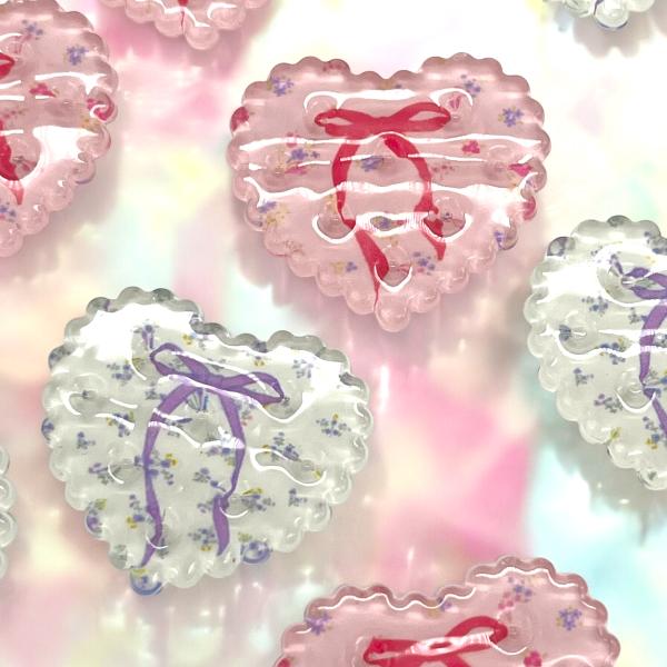 ご覧になって頂きありがとうございます。クリアのハートのモチーフのアクリルパーツです。リボンのデザインも可愛いのでヘアアクセサリーや、バックなどに付けたりいろいろな用途でご使用ください。【内容数】同色4個【サイズ】約2.5cm×3cm 厚み約...