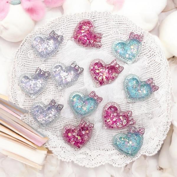 愛らしいハート型のアクリルパーツです。透明な樹脂の中にキラキラのグリッターが封入されており、光の反射で美しく輝きます。上部にはリボンのモチーフが付いており、とても可愛らしいデザインです。◆用途◆・ハンドメイドアクセサリー制作・デコレーション...