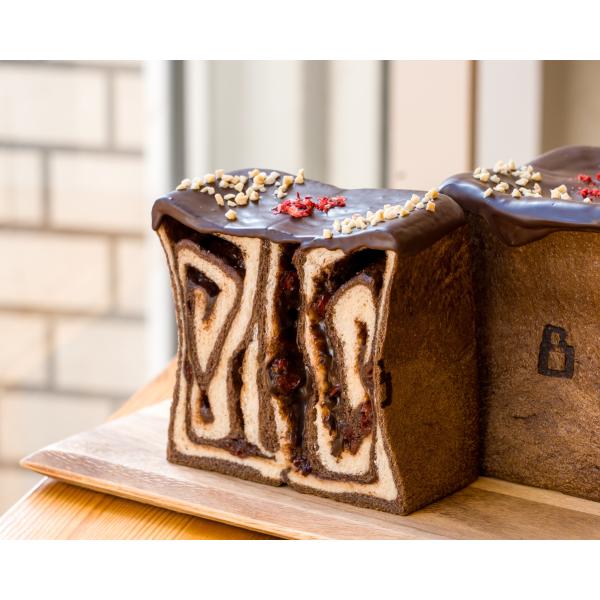 [Release date: January 19, 2026]ヘーゼルナッツのチョコクリームとドライクランベリーが入ったブラックココアを練り込んだ２層生地。上掛けのチョコにはアーモンドとドライストロベリーを散りばめて。