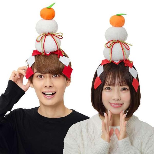 かがみもちカチューシャ。白いもちもち鏡餅が乗ったカチューシャ。みかんのような橙（だいだい）や御幣（紅白の紙）などもついてリアルです。ボリュームのある鏡餅なので着用する時は落とさないように気を付けて下さいね。