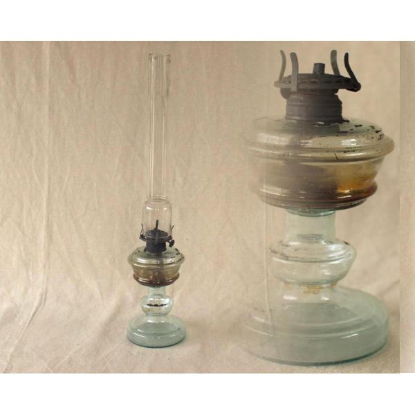 明治〜大正期ごろのガラス製オイルランプです。電球がまだ普及していなかったころ、部屋の明りを取るのに使用されていました。シンプルで美しく薄く青みがかったガラスの台座とスッと伸びたホヤ（火屋）が上品な意匠です。錆びて朽ちないように金具部分は上質...