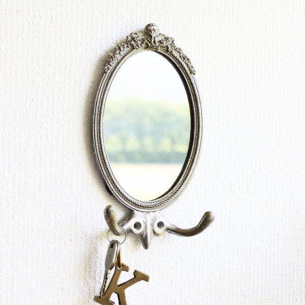 壁面を飾るフック付きのアイアンミラーは頬杖をついた大きな羽のエンジェルがお花に囲まれているデザイン身だしなみをチェックするのに重宝する小さめサイズで毎日身に着けるアクセサリーや小物を引っ掛けて置く事が出来ます商品名 ： フック付きウォールミ...