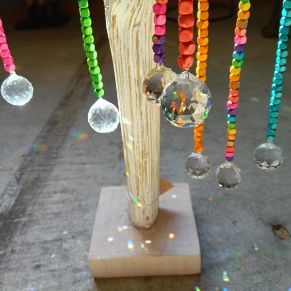 カラフルなウッドビーズのサンキャッチャーです。窓辺や窓際に飾ると、太陽光を受けて色彩豊かに輝き、美しいプリズムが広がります。サンキャッチャー (Suncatcher) とは、太陽光をプリズムのように透過・屈折させるガラスなどで作られたインテ...