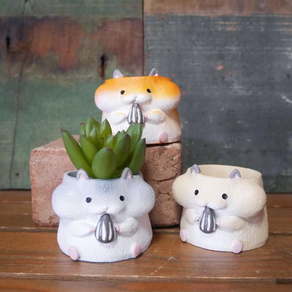 おもわず集めたくなるような、ひまわりの種をくわえたハムスターがかわいいリトルレジンポットです。1号ポットが入る小さめな鉢。多肉植物はもちろん、プリザーブドフラワーのアレンジでもピッタリです。サイズ：幅60×奥行58×高さ48mm（約）内寸：...