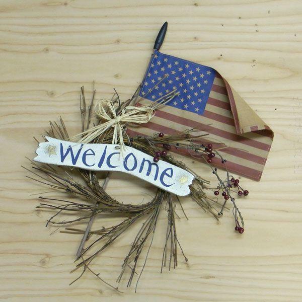 小枝のリースに星条旗をを組み合わせたアメリカンなウエルカムリース。サイズ：幅38×長さ48cm　企画：アメリカ　製造：中国