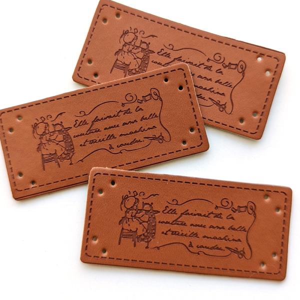 ミシンに向かいお裁縫中の女の子と英字が入った革タグ3枚セット。ナチュラルで使いやすい柄です。■サイズ:約25mm×55mm■素材：合成皮革■ご注意：サイズの誤差、歪み、小さな欠け、色の濃淡差、プリントずれ、バリ、小キズ、塗装ムラなど見られる...