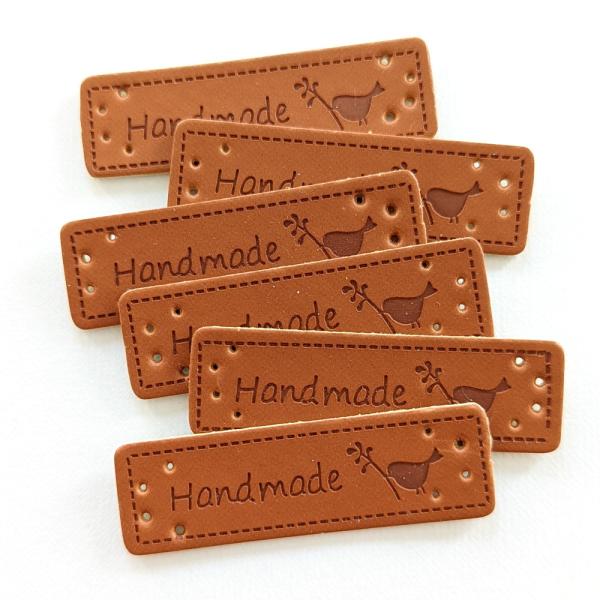 可愛い小鳥のシルエットとHANDMADEの文字が入った革タグ3枚セット。他の種類も販売中です。お得な15枚セットも販売しております。◆サイズ:約15mm×50mm／厚み＝約1.2mm程度◆素材：合成皮革■ご注意：サイズの誤差、歪み、小さな欠...