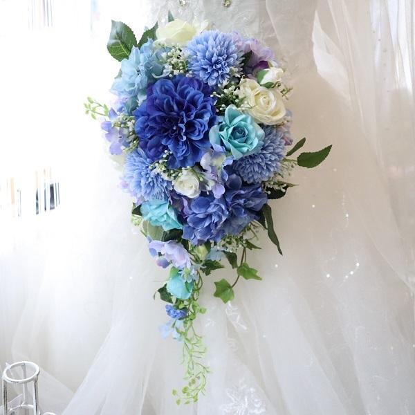 ダリアのロイヤルブルーを基調としたキャスケードブーケです。清楚なブルーが映える優雅でノーブルなスタイルはもちろんのこと、ナチュラルなグリーンに合わせた開放感あふれるスタイルにもぴったりです。◆使用花材ダリア　ピンポンマム　ブルースター　デル...