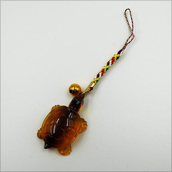 長寿や健康を願う縁起物の亀根付。古くから縁起の良い生き物とされ、長寿の象徴として親しまれています。根付紐は赤・白・黄・紺・黄緑の5色が組み合わさり、華やかさをプラス。お土産やプレゼントとしても喜ばれます。サイズ：全長約12cm、亀部分 約4...