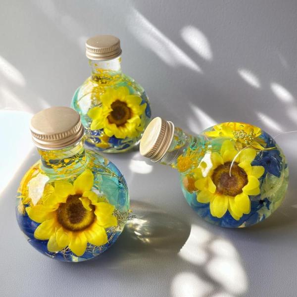 ひまわりハーバリウム季節を問わず大人気のひまわりとさくらを閉じこめたハーバリウムです。生花のヒマワリはとても美しいのですが、自然のものなのでどうしても個体差があったり、花びらの動きが一定でないこともあります。そこで、高級造花を使用したハーバ...