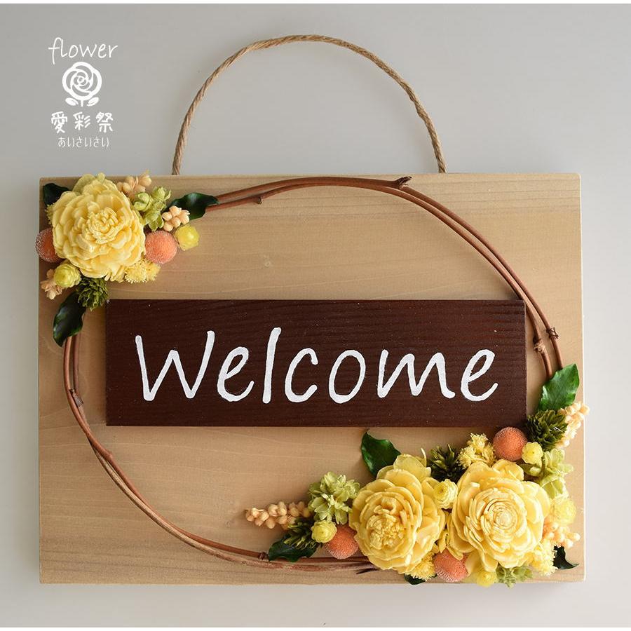 玄関ドアに イエロー系のお花のフレームアレンジ welcomeプレート付き