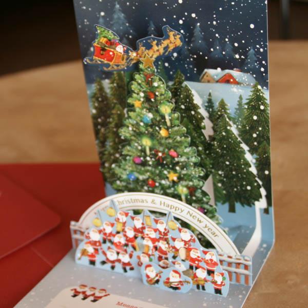 立体クリスマスカード 大きなツリーの前でサンタ楽団の行進 縦開き