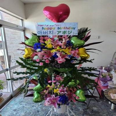 ピンクのゆりと季節のお花でハートのバルーン付きスタンド生花2段に！ |  | 03