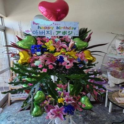 ピンクのゆりと季節のお花でハートのバルーン付きスタンド生花2段に！ |  | 04