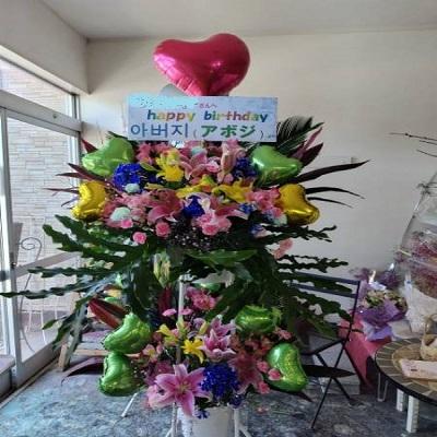 ピンクのゆりと季節のお花でハートのバルーン付きスタンド生花2段に！ |  | 05