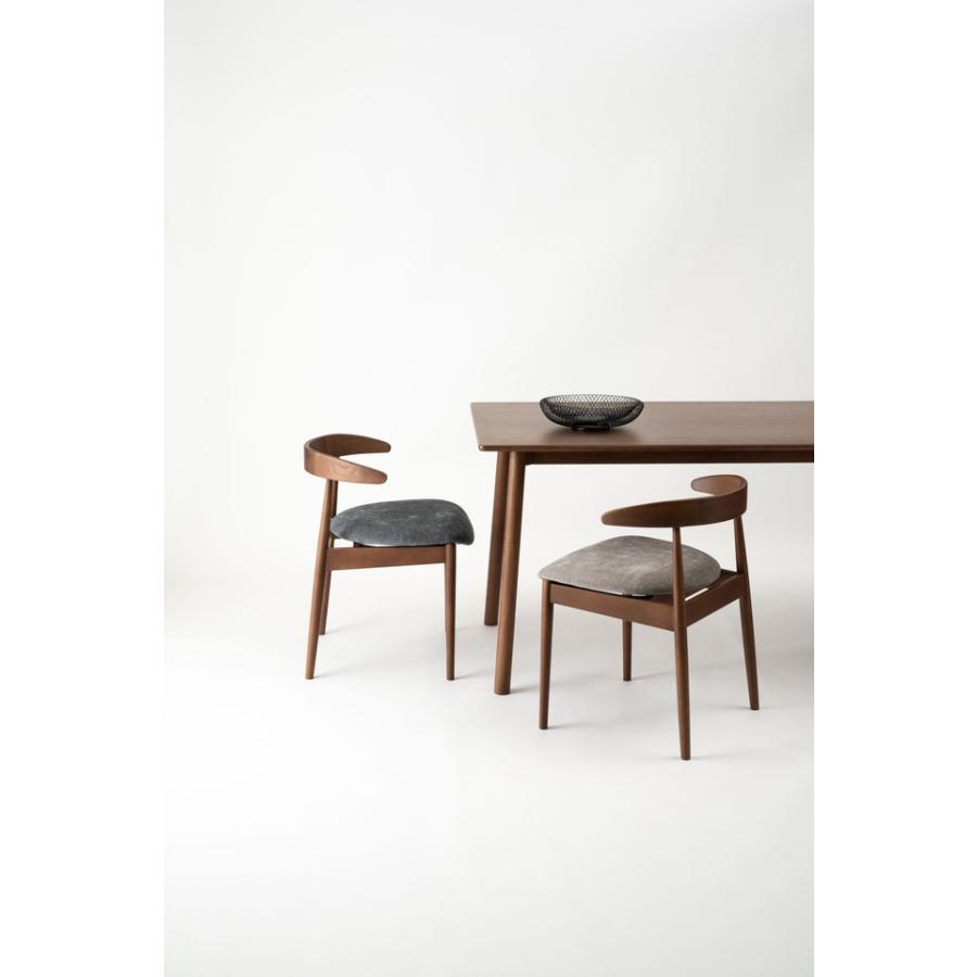 肘掛けをテーブルに掛けて脚を浮かせるシンプルモダンなダイニング