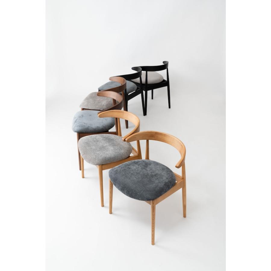 肘掛けをテーブルに掛けて脚を浮かせるシンプルモダンなダイニング